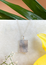 Load image into Gallery viewer, Silver Minerva Pendant on white marble slab with leaves and flowers.