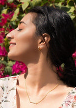 Load image into Gallery viewer, Model wearing minimal sleek bar necklace sitting in front of bougenvellia