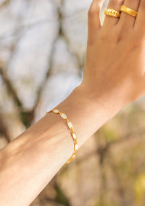 Model wearing Tia bracelet and rings with blue background