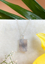 Load image into Gallery viewer, Silver Minerva Pendant on white marble slab with leaves and flowers.
