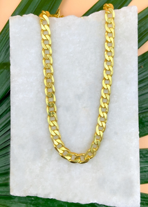 Cuban chain over marble slab and green leaves