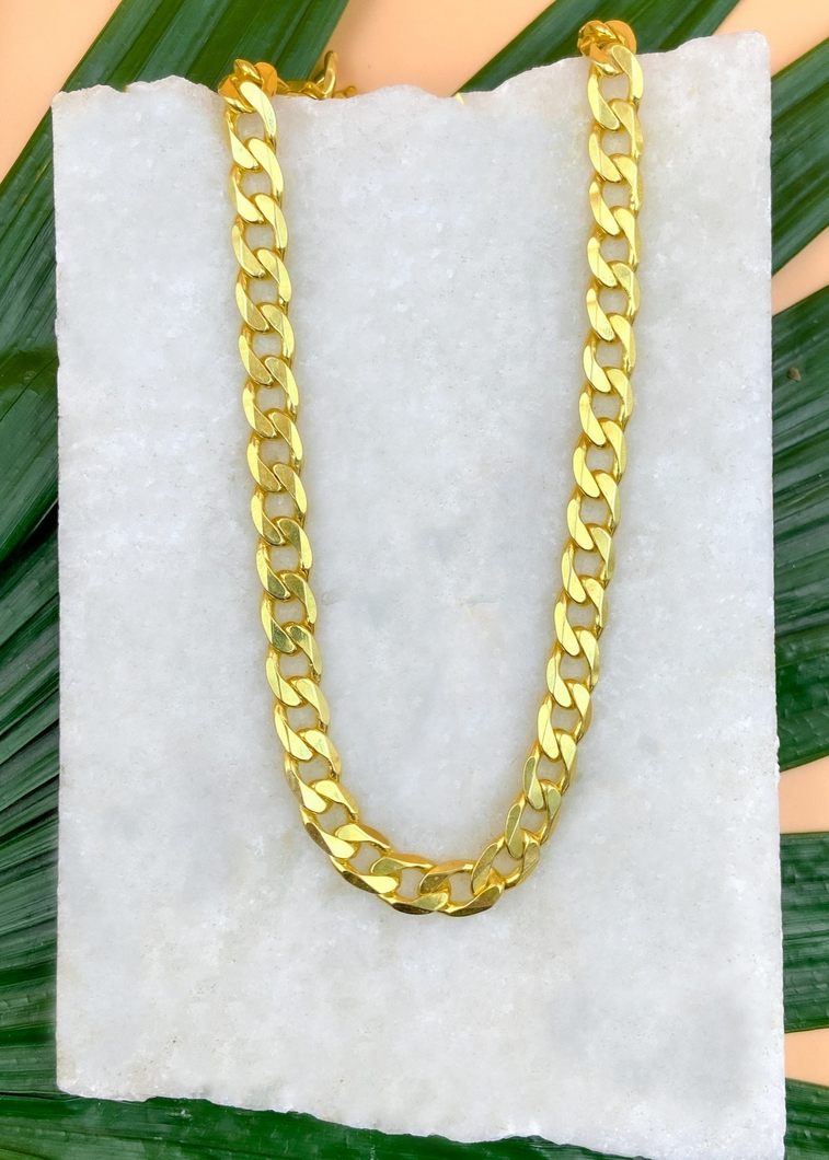 Cuban chain over marble slab and green leaves