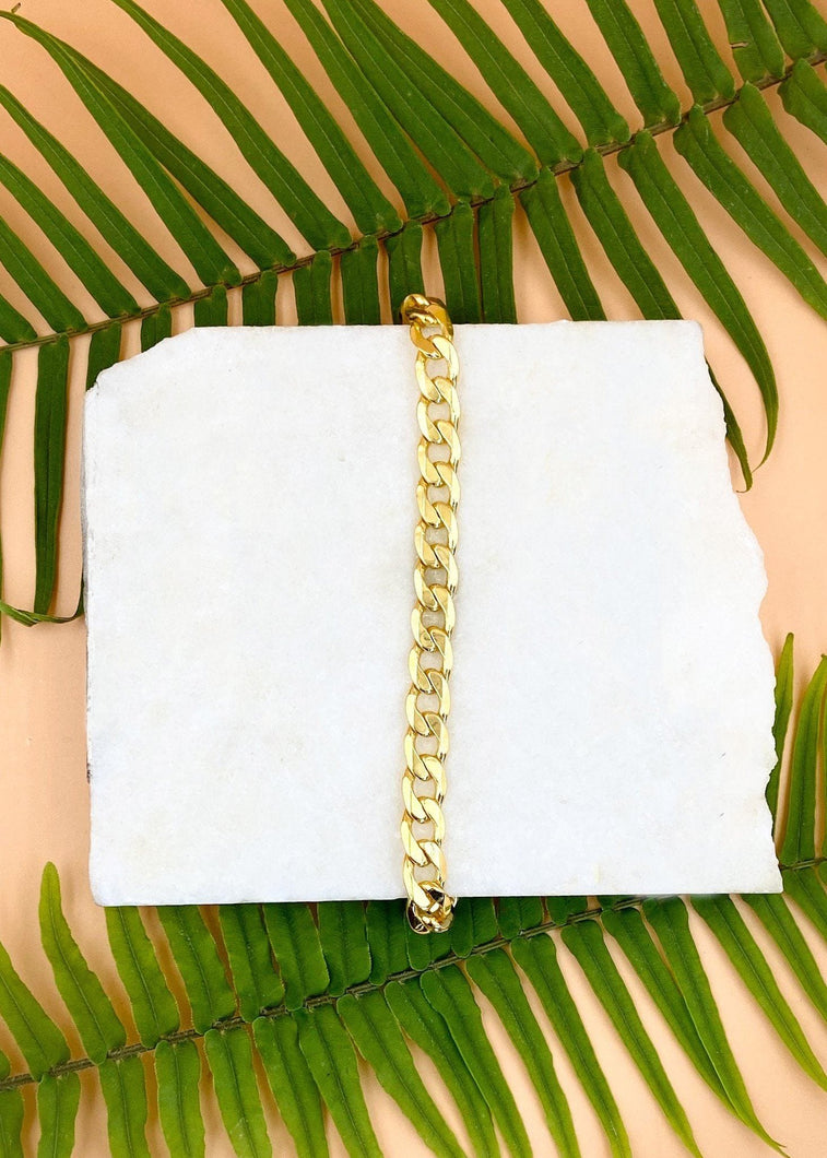 Cuban bracelet on marble slab over fern leaves