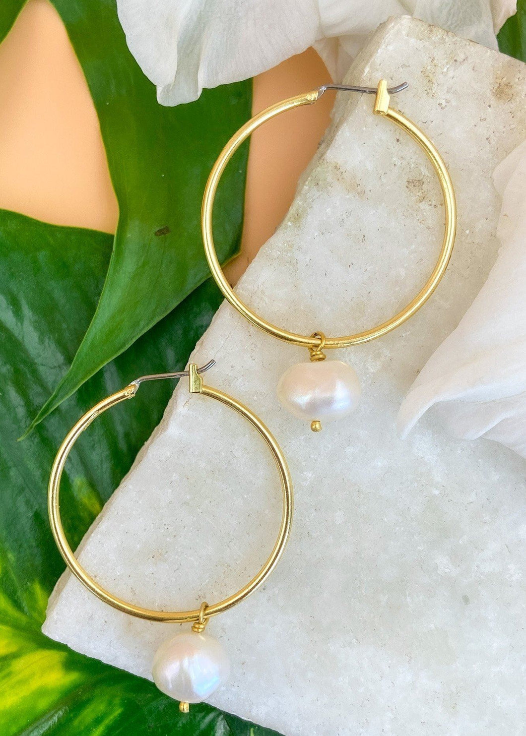 Natural Pearl hoops on marble and green leaves