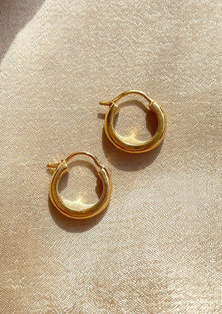 Dainty bold hoops earrings on golden cloth background