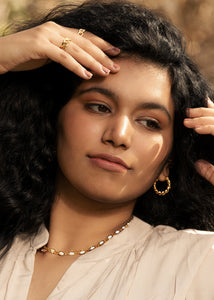 Model with curly hair wearing rings, earrings and necklace