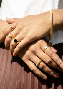 Adira bracelet with different rings on a model wearing maroon pleated skirt