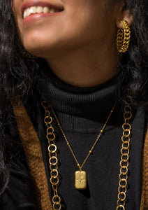Model wearing Celeste Pendant, Enso Necklace and Aphrodite Earrings on black top