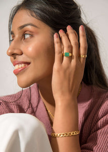 Model wearing rings and cuban bracelet wearing pink sweater